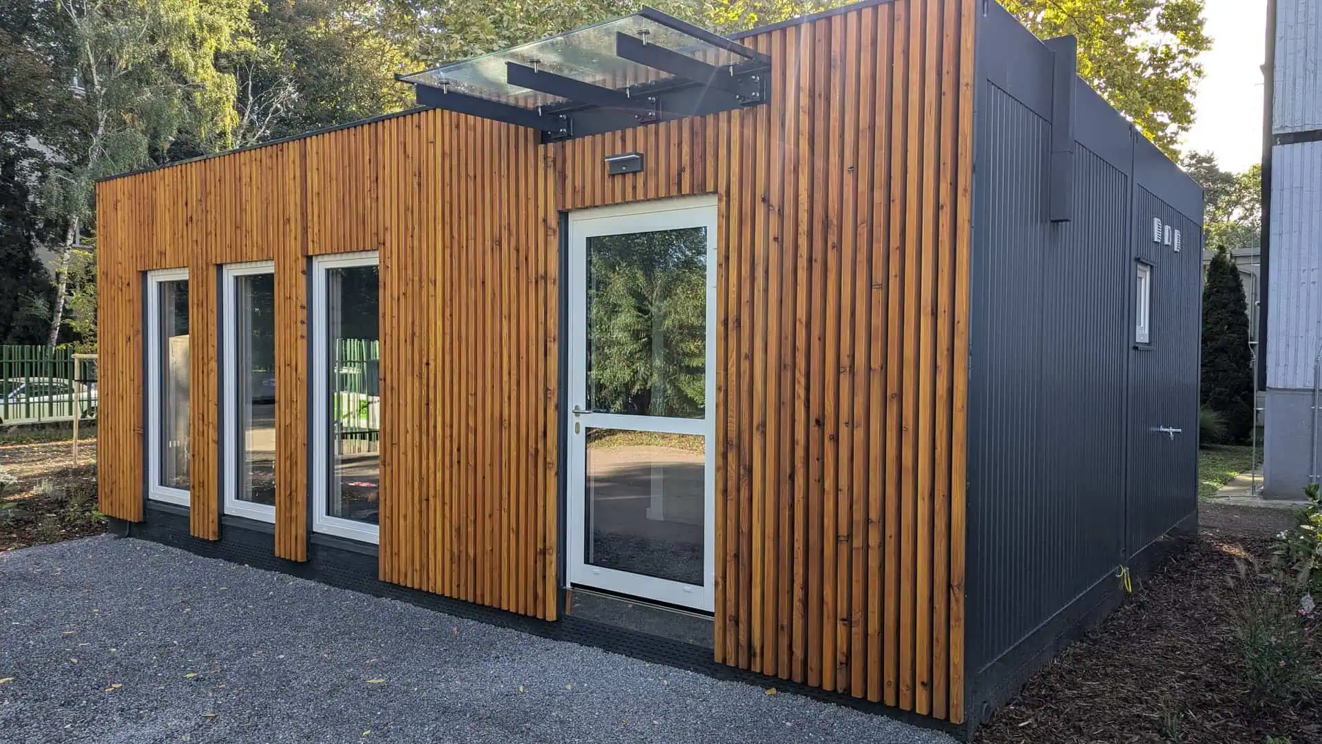 Exteriér modulárneho kaderníckeho salónu v Trnave s dreveným obkladom a vstupom s prístreškom