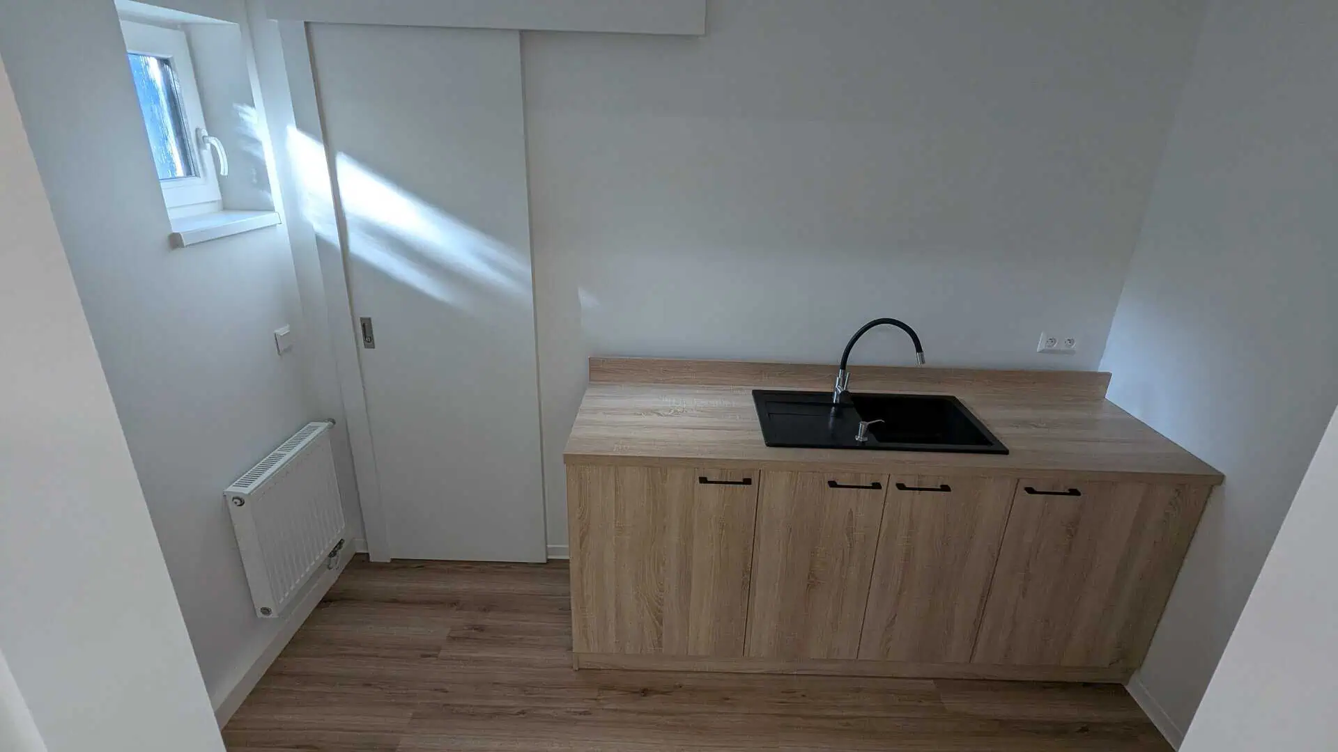 Kuchynský kút v modulárnej budove kaderníckeho salónu v Trnave – drevená linka s čiernym drezom